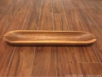 Wooden serving tray placed on a wooden floor for size and detail reference.
