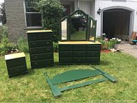 Photo showing entire 5 piece green painted oak bedroom set outdoors on grass, including night table, highboy dresser, dresser with tri-fold mirror, and queen headboard laid in front.