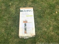 Photo of the cabinet in its original packaging box on grass, showing brand and basic features.