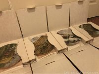 Four Christian Bell collector plates in original packaging, showing partial detailed painted historical scenes.