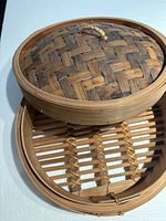 Open bamboo steamer showing woven lid interior and slatted base