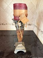 Burgundy pillar candle with Capri tag on ornate metal pedestal holder