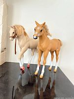Both plastic horse figurines standing side by side