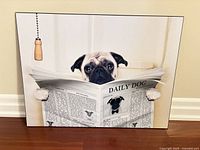 Front view of the pug dog photo wall art on wood panel, showing full image, black edge, and hanging pull cord visible