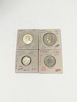 Four silver coins in holders: Panama 1⁄4 Balboa, Dominican Republic 1⁄2 Peso, Germany 1 Mark, France 20 Centimes