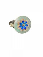 Angular view of ring showing jade disc and blue enamel flower