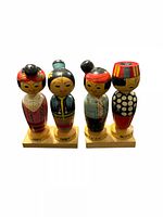 Front view of four wooden bobble dolls on bases