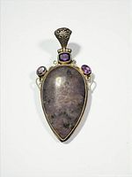 Front view of pendant showing kiwi jasper cabochon and three amethysts