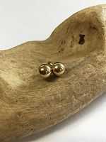 Close-up of both gold ball studs on wood prop