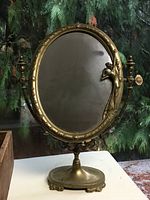Full view of brass swivel vanity mirror on pedestal base