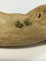 Both peridot stud earrings front view on wood prop