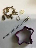 All items laid out showing bracelet, rings, hat pins and cookie cutter