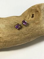 Pair of amethyst stud earrings on driftwood background