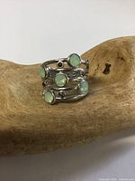 Front view showing five pale green cabochon stones and dark accents in sterling silver setting