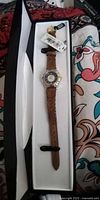 Watch in original box, tags visible, full view of dial and strap