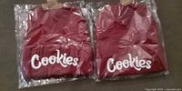 Two sealed red Cookies beanies in clear plastic
