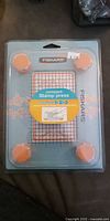 Front of sealed Fiskars compact stamp press showing grid surface and orange foam feet