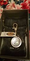 Watch in pouch showing Fossil tag, clasp, dial and Nine West branding on pouch