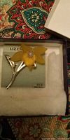 Overall view of Liz Claiborne yellow flower pendant on display card in box