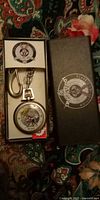 Pocket watch, chain, belt clip, and branded box visible
