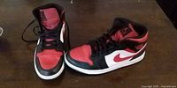 Pair of red/black/white Nike Air Jordan 1 sneakers on tabletop