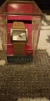 Nine West watch in clear plastic retail box showing dial, strap, price tag