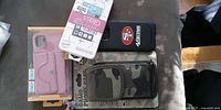 All four smartphone accessories: pink wallet case, packaged glass screen protector, black 49ers case, camouflage phone pouch