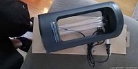 Sansi UV sanitizer lamp lying on cardboard with power cord visible