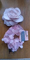 Scrunchie with tag and fabric rose hair clip on wooden surface
