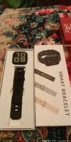 Smartwatch in open retail box alongside image of product and strap options