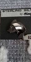 Front view of sterling silver fish brooch on display card