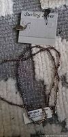 Necklace coiled with earrings card showing sterling silver mark and price tag