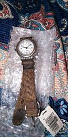 Front view of Fossil watch on bubble wrap showing dial, case, leather strap, and hangtag