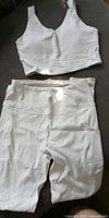 White sports bra style crop top and matching leggings laid flat