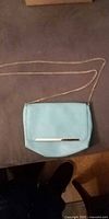 Full view of mint crossbody purse showing flap, gold bar accent and chain strap