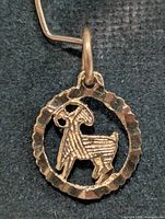 Front view of 10K gold Aries pendant showing ram motif within scalloped frame