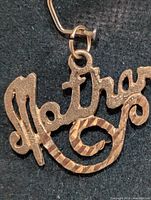 Front view of 10K gold “Mother” pendant showing texture and script