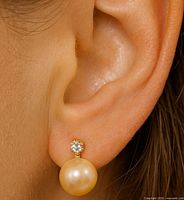 Earring worn on ear showing scale of pearl and diamond