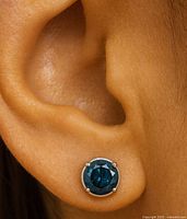 Blue diamond stud earring shown worn on ear