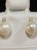 Front view of both pearl and diamond stud earrings on card