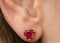 Ruby stud earring worn in ear showing scale and gold setting