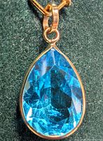 Front view of pear-shaped blue topaz pendant in 10k gold bezel