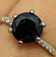 Close-up of ring on finger showing black diamond solitaire and prong setting