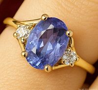 Close-up of ring on finger showing tanzanite and two diamonds