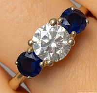 Ring on finger showing central moissanite and side sapphires
