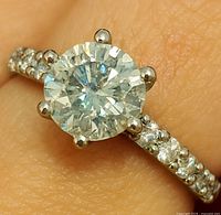 Ring on finger showing moissanite center and diamond band