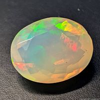 Oval faceted opal showing play‐of‐color on black background
