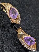 Close view of front of both earrings showing amethyst stones and clear accents