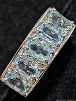 front view showing five oval blue topaz stones with clear accents in silver setting