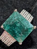 Top view of ring showing emerald-cut green stone and triple-row shoulders